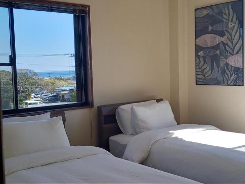 two beds in a room with a large window at Villa Nami in Kashima