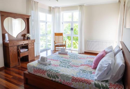 a bedroom with a bed and a dresser and windows at Casa D Aitana in Pardaces de Arriba