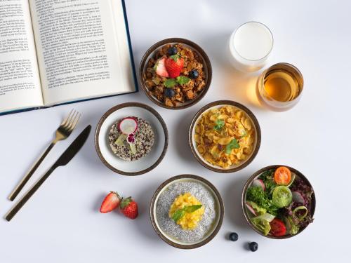 a table with plates of food and a book at Montraj Coach Sukhumvit Bangkok in Bangkok