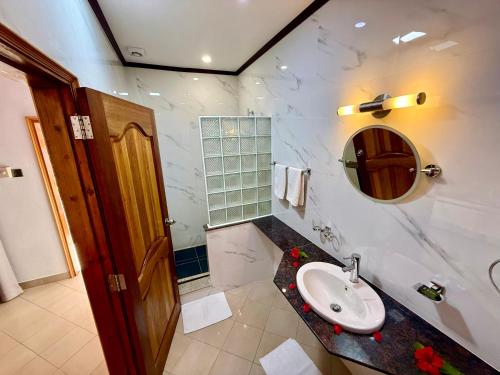 a bathroom with a sink and a mirror at Beach Villa Guesthouse in Grand Anse