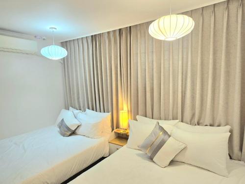 a bedroom with two beds and two lamps and curtains at 원하우스 in Seoul