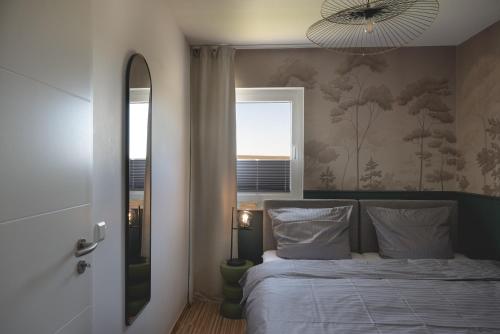 a bedroom with a bed and a window and a mirror at Design-FeWo Fleesensee, Wallbox, Sauna, Terrasse in Unter Göhren