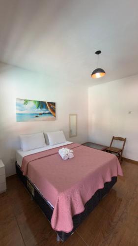 a bedroom with a large bed with a pink blanket at Estadia Cipó Pousada & Piscina in Serra do Cipo