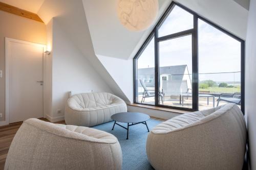 a living room with two chairs and a table at Aux flots de la Torche, 3ch in Penmarch