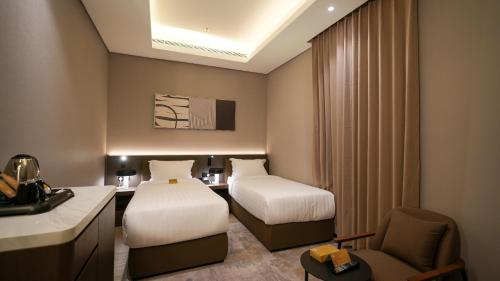 a hotel room with two beds and a chair at سنود النرجس Snood Al Narjis in Riyadh