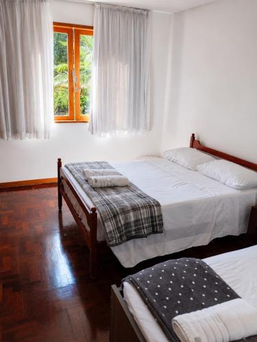 a bedroom with two beds and a window at Refúgio na Serra - natureza e conforto in Teresópolis