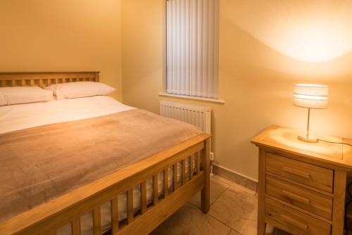 1 dormitorio con 1 cama y 1 mesa con lámpara en Elagh Cottages, en Derry Londonderry