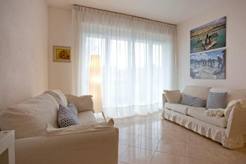 a living room with a white couch and a window at Casa Gorgone, SeaFront Flat! in Viareggio