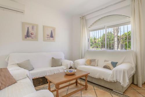 a living room with two white couches and a table at Chalet Fuente2 piscina común famila in Conil de la Frontera