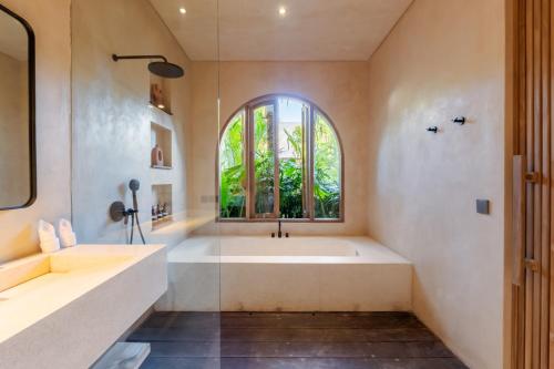 a bathroom with a large tub and a window at La Isla Boutique Residences in Uluwatu
