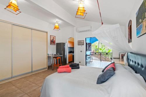 a bedroom with a large bed and a kitchen at Studio Lili in Le Diamant
