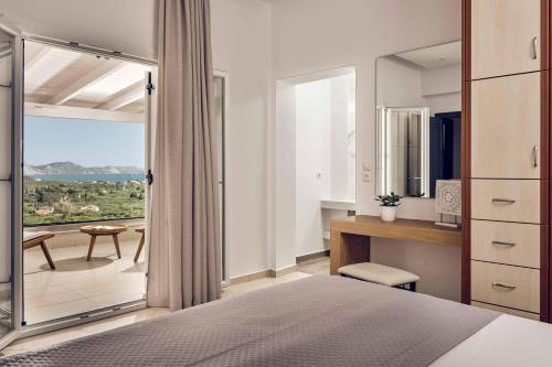 ein Schlafzimmer mit Bett, Schreibtisch und Balkon in der Unterkunft Ether Villa View in Lithakia