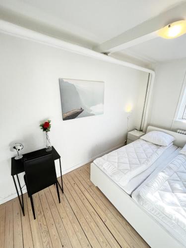 a white bedroom with a bed and a table at Central Large Double Room with free parking in Aalborg