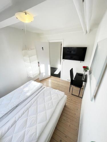 a white bedroom with a bed and a table at Central Large Double Room with free parking in Aalborg