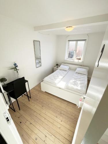 a small white bedroom with a bed and a desk at Central Large Double Room with free parking in Aalborg