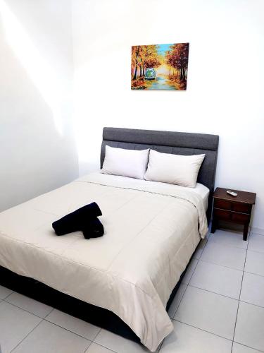 a bed with a black hat sitting on top of it at Homestay Bunga Raya Wifi Netflix in Sitiawan