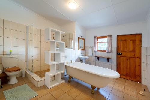 a bathroom with a tub and a toilet and a sink at Emma's Place in De Rust