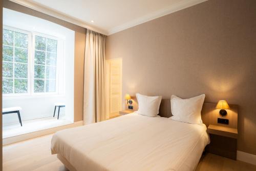 a bedroom with a white bed and a large window at Hotel Lodewijk Van Male in Bruges