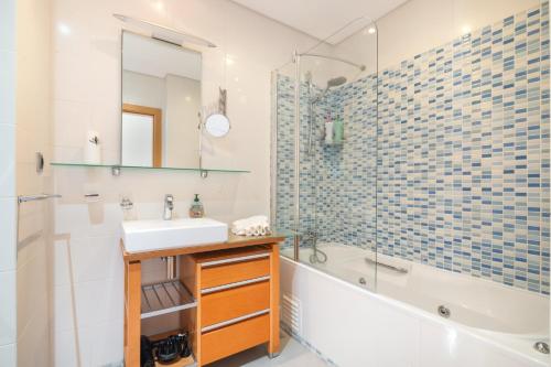 a bathroom with a sink and a tub and a shower at Parque Atlântico Apartment in Quarteira