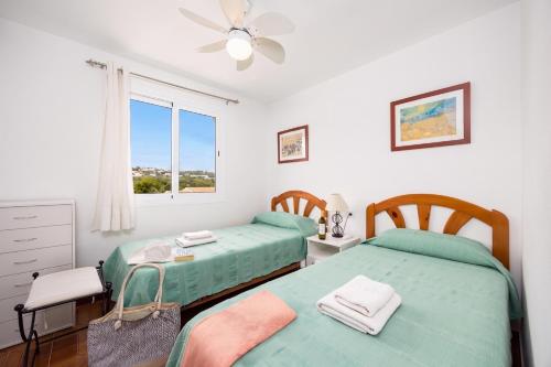 a bedroom with two twin beds and a window at Villa Ponent in Port d'Addaia