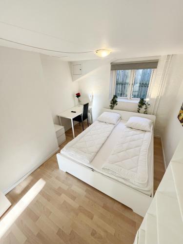 a white bedroom with a bed and a table at Central Large Double Room with free parking in Aalborg
