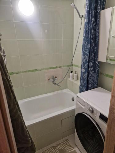 a bathroom with a tub and a washing machine at Cozy 3 room appartment in Klaipėda