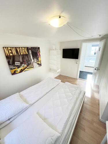 a white bedroom with a bed and a tv at Central Large Double Room with free parking in Aalborg