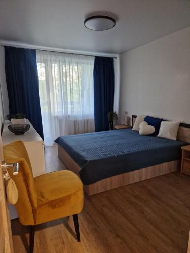a bedroom with a bed and a chair and a window at Cozy 3 room appartment in Klaipėda