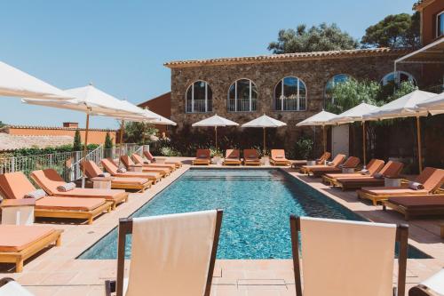 a swimming pool with lounge chairs and umbrellas at Finca Victoria, a Member of Design Hotels in Begur