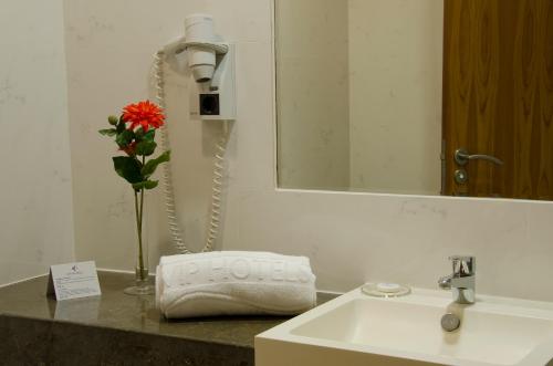 - un lavabo dans la salle de bains avec un téléphone et un vase avec une fleur dans l'établissement VIP Executive Santa Iria Hotel, à Santa Iria da Azóia