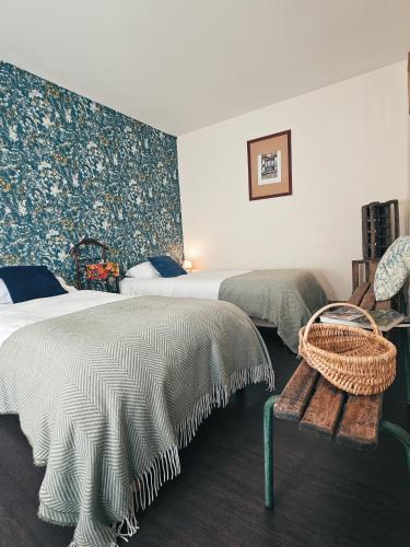 a bedroom with two beds and a wicker bench at Auberge de Chanteuges in Chanteuges