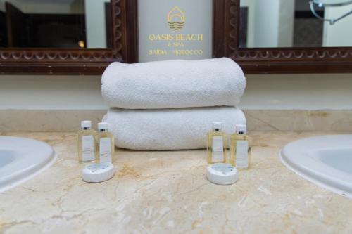 a bathroom with three sinks and a stack of towels at Oasis Beach & Spa - Blue Pearl in Saïdia