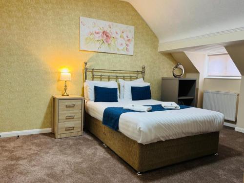 a bedroom with a large bed with blue and white pillows at Trivelles Belforte Hotel , Sale, Manchester - M33 2AE in Sale