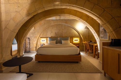 a bedroom with a bed in a stone wall at The Vincent Boutique Hotel, BW Premier Collection in Valletta