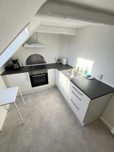 a kitchen with white cabinets and a black counter top at Bright and central city apartment near Aalborg Bus in Aalborg