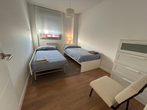 a small room with two beds and a chair at TÍA NANDUCA in Liencres