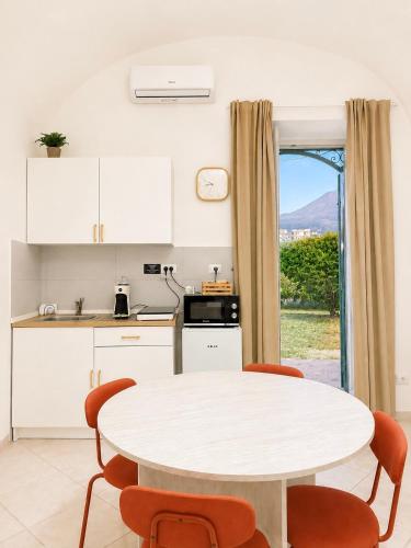 a kitchen with a white table and chairs and a window at Casa Corallium in Torre del Greco