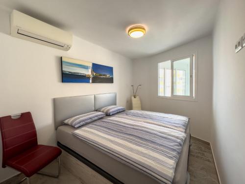 a bedroom with a bed and a red chair at Increíbles vistas al mar A102 in Torrox Costa