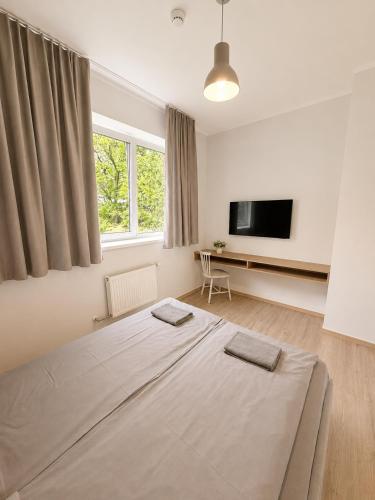 a bedroom with a bed and a flat screen tv at Glūdas Grava in Cēsis