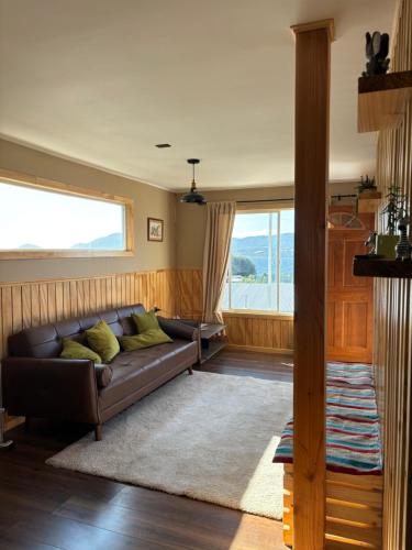 a living room with a couch and a large window at Cabañas Lago Huillinco in Chonchi