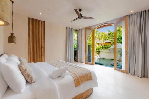 a bedroom with a white bed and a large window at La Isla Boutique Residences in Uluwatu