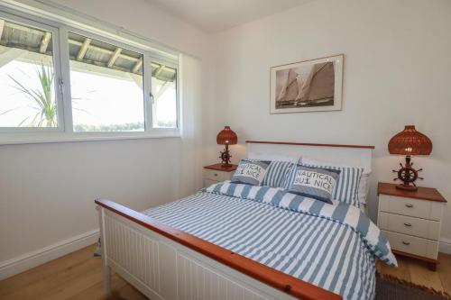 a bedroom with a bed and two windows at Rollies Retreat in Fowey