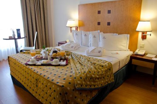 a hotel room with a bed with a tray of food on it at VIP Executive Santa Iria Hotel in Santa Iria da Azóia