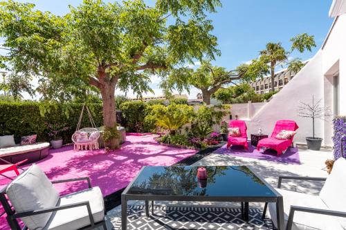 a patio with pink furniture and a tree at Villa L'Hyliadenna avec jardin - parking privé - au cœur du Village Naturiste, NaturaBeach Héliopolis - Plage à pied in Cap d'Agde