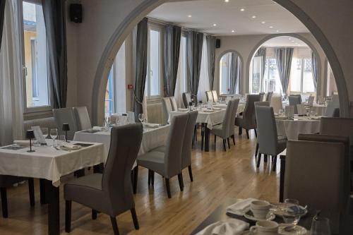 a restaurant with white tables and chairs and windows at Hôtel Restaurant Le Plat d'Etain in Brou