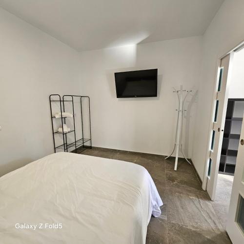 a white bedroom with a bed and a flat screen tv at Aires de Benatae in Benatae