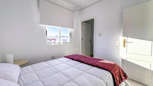 a white bedroom with a bed and a window at Apartamento Luz de Almoradi in Almoradí