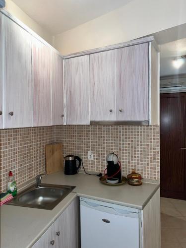 a kitchen with white cabinets and a sink at Sea and Stone Apartment in Afitos