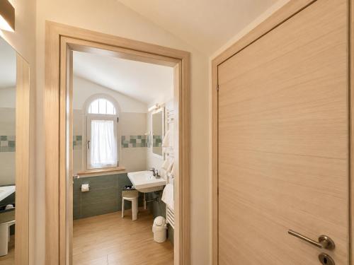 a bathroom with a wooden door and a sink at Hotel Residence Vallecorsa in Vada