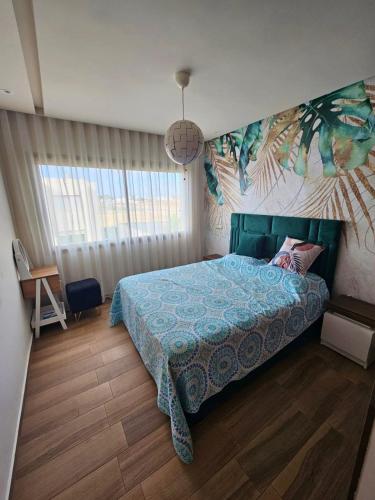 ein Schlafzimmer mit einem Bett mit blauer Bettdecke in der Unterkunft Bleu Beach uniquement pour famille in Sidi Rahal
